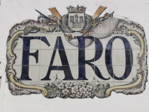Artfully designed tile painting with Faro lettering and a coat of arms on a wall, Faro, Algarve,