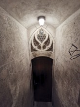 Stone staircase in an old building leading to a decorated door with graffiti on the walls, Ulm