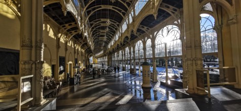 Large, sun-drenched interior of a historic hall with arched windows and columns, wellness,