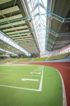 Extensive sports hall with green running track and stands, large windows, Sindelfingen Glass