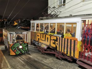 Two graffiti-painted funiculars travel illuminated through the night, Historic funicular, Elevador