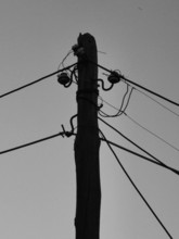 Monochrome silhouette of a power pole with wires, clear sky in the background, Albania
