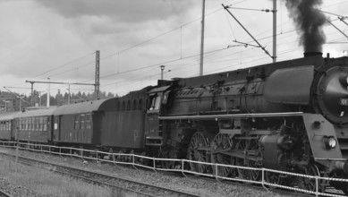 Historic steam locomotive on rails, smoke rising from the chimney