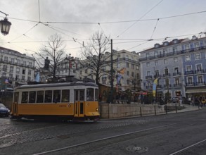 A yellow, historic tram stands in the city center at dusk, Lisbon, Portugal