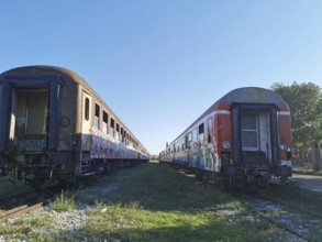 Two abandoned trains on parallel tracks covered by graffiti, former Deutsche Bahn, Albania