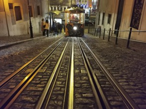 Front view from track perspective, graffiti-painted funicular runs illuminated through the night,