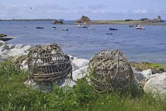Large rope rolls lie on the shore with a wide view of the sea and several boats, lobster cages, St