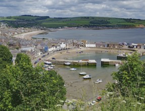 Coastal view of a village with harbour, boats and green hills under a cloudy sky, Stoneheaven,