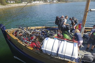 People loading a boat with bikes and luggage on a clear summer day in the harbour, Knoydart,