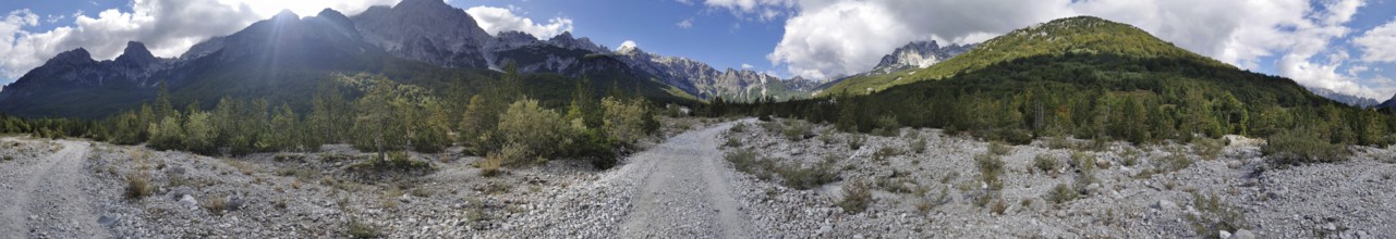 Panorama, dirt road through a wooded mountain landscape under a cloudy sky, Albanian Alps National