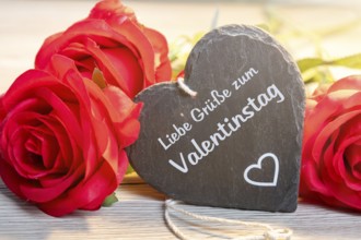 Red roses and (slate) heart with the inscription LIEBE GRÜSSE ZUM VALENTINSTAG