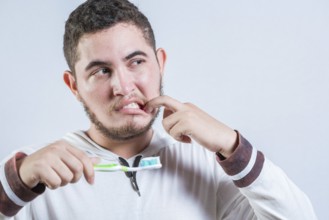 Young man with tooth sensitivity holding a toothbrush isolated. Man suffering from gum pain holding