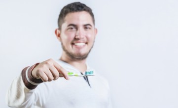 Portrait of happy young man showing toothbrush with toothpaste