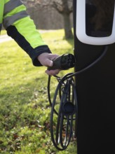 Worker holding an ev charging cable, representing sustainability and green energy
