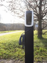 Ev charging station standing in green grass, promoting sustainable transportation