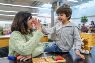 Mother and young boy high fiving, sharing a moment of success and happiness while playing a wooden