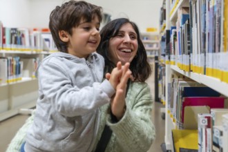 Parent and young child are sharing a joyful high five gesture while standing in a brightly lit