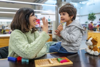Mother and son smiling and high fiving while playing a colorful block strategy game at home,