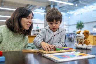 Teacher and young boy engaging in educational play, carefully fitting colorful geometric blocks