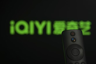 Dhaka, Bangladesh- 21 Jan 2026: Close-up of a smart TV remote control against a blurred iQIYI logo