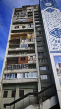 The colorful façade with windows, balconies, laundry, of a tall, old, partly dilapidated