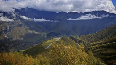 Panoramic view of an autumn mountain landscape under dramatic clouds, Stepantsminda, Caucasus,