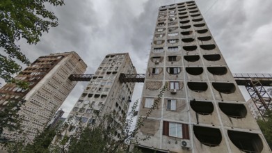 Three high-rise buildings connected by metal bridges under cloudy skies, nostalgic charm,