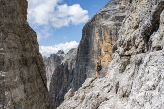 Hikers on the Sentiero Brentari via ferrata in front of cliffs, Brenta Mountains, Brenta-Adamello