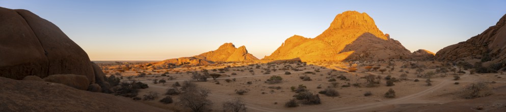 Mountains in the desert at sunset with bright shades of orange on the horizon, Spitzkoppe, Namibia