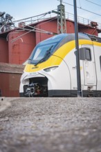 Modern locomotive on rails against an industrial backdrop under grey skies, opening of the Hermann
