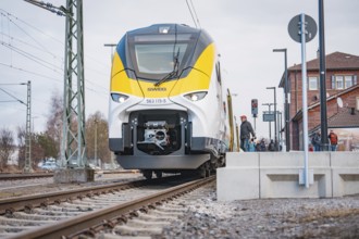 Modern locomotive on railroad tracks in front of buildings and power lines, opening of the Hermann