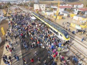Large crowd at an event with train and cranes on a construction site, opening of the Hermann Hesse