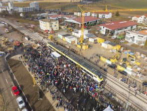 People gather around a train on a construction site, aerial view with landscape in the background,