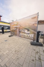 Advertising banner for the Hermann Hesse Railway on a platform, with a train in the background,