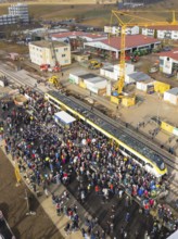Large crowd in front of a train on a construction site, aerial view with crane in the background,
