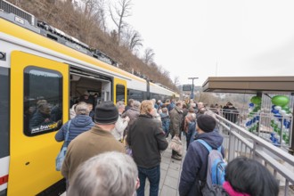 People standing on a platform next to a decorated train, platformside celebration, opening of the