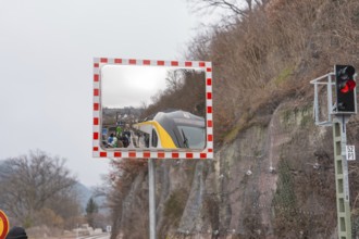 A mirror depicts a train and people waiting in a landscape, opening of the Hermann Hesse Railway,