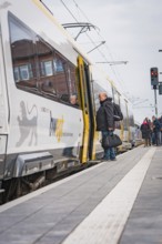 People board a train at a train station with a cool, cloudy atmosphere, opening of the Hermann