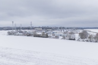 A wide snowy field with power lines and a substation in the distance, substation, Jettingen,