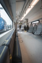 Interior view of a modern train with windows and folding seats, Siemens Micro Plus B battery