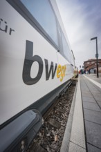 Side close-up of a moving branded train standing on the railway track, with clear sky in the