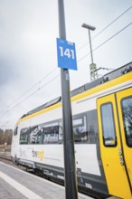 Side view of a yellow train with a track sign on the platform, battery electric train Siemens Micro