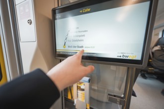 Display screen with timetable and hand showing departure time, battery electric train Siemens Micro