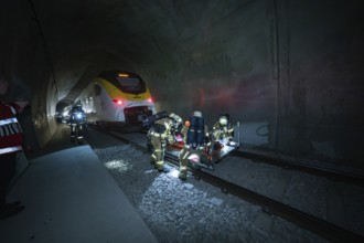 Firefighters during a rescue operation in a dark railway tunnel with a train, fire drill on the