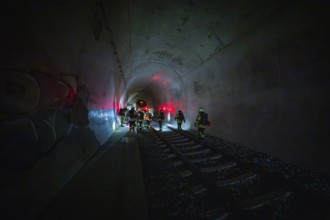 Groups of firefighters work in an illuminated tunnel with a dramatic atmosphere, fire drill on the