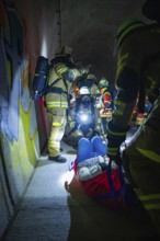 Firefighters provide first aid to an injured person in a dark tunnel, fire drill on the