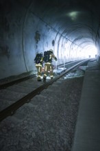 Firefighters in protective suits walk through a dark tunnel on tracks, fire drill on the Hermann