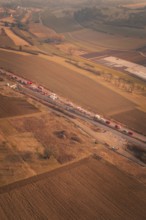 Emergency vehicle convoy on country road in vast, hilly landscape at dusk, fire drills on the