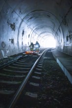 Firefighters on a rail vehicle in a tunnel, light visible at the end, fire drill on the