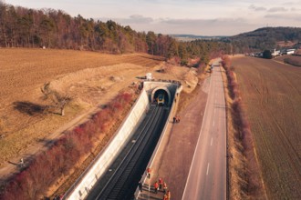 Aerial view of a railway tunnel next to a road and emergency services surrounded by trees, fire